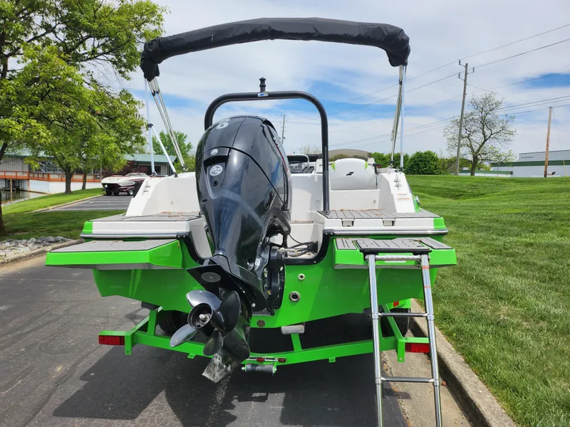 Slide: The Image of 2023 Starcraft SVX 191 OB boat with outboard motor and swim ladder, parked on pavement. - 2