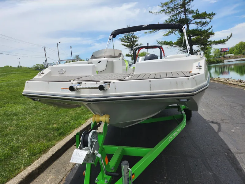 Slide: The Image of 2023 Starcraft SVX 191 OB boat on a green trailer, parked near a lake. - 6