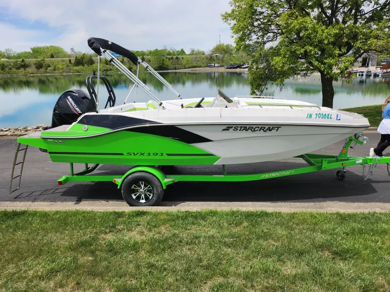 Slide: The Image of 2023 Starcraft SVX 191 OB boat on a vibrant green trailer by a lake. - 9