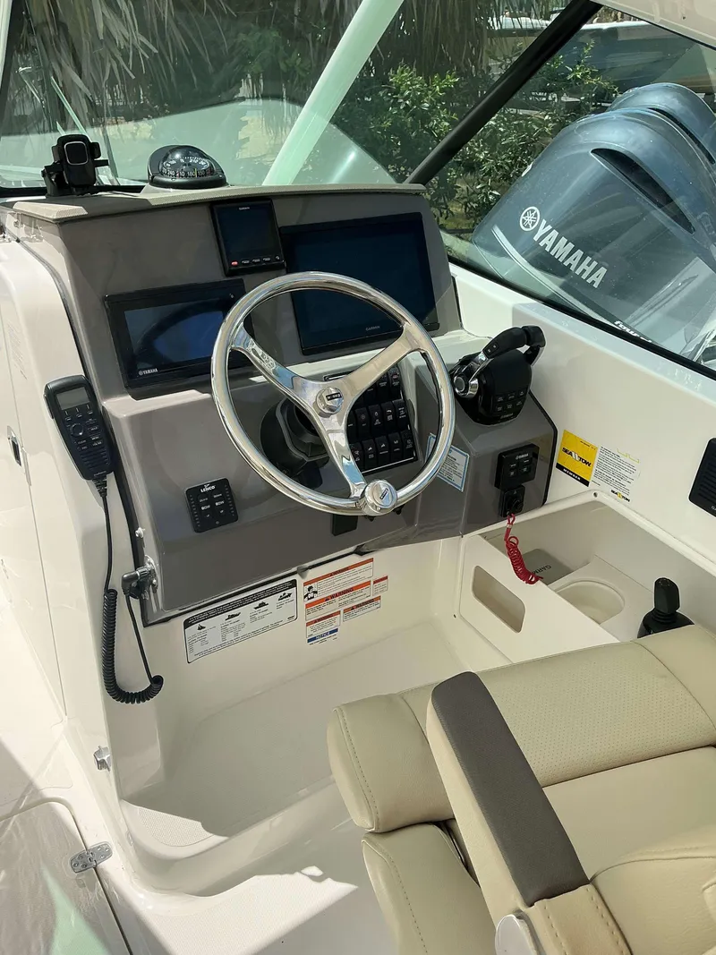 Slide: The Image of 2020 Pursuit DC 266 boat helm with steering wheel, Yamaha controls, and navigation screens. - 13