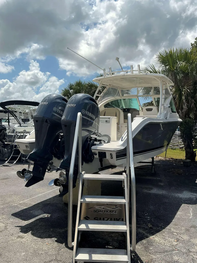 Slide: The Image of 2020 Pursuit DC 266 boat with twin Yamaha engines, parked outdoors under cloudy skies. - 2