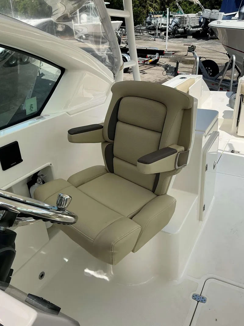 Slide: The Image of Captain's chair on 2020 Pursuit DC 266 boat, featuring beige upholstery and armrests. - 5