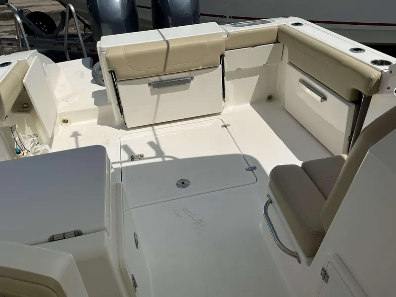 Slide: The Image of 2020 Pursuit DC 266 boat interior with beige seating and storage compartments. - 8