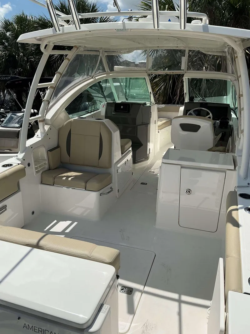 Slide: The Image of 2020 Pursuit DC 266 boat interior with seating and helm, under sunny skies. - 9