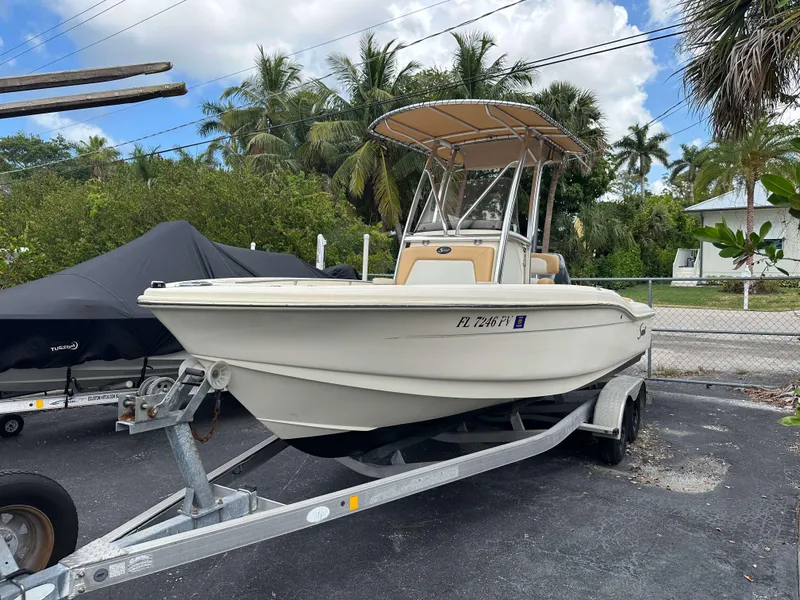 Slide: The Image of 2014 Scout 215 XSF boat on trailer, parked outdoors with palm trees in background. - 1