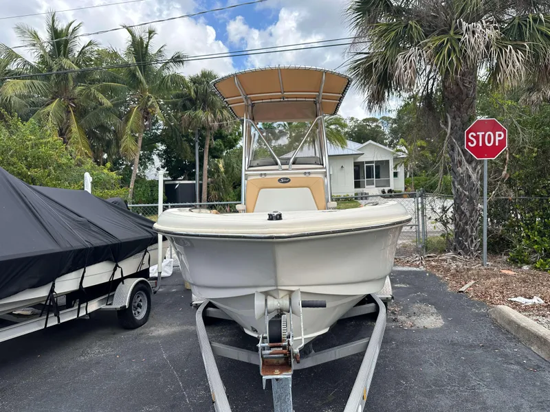 Slide: The Image of 2014 Scout 215 XSF boat on trailer, parked near palm trees and stop sign. - 2