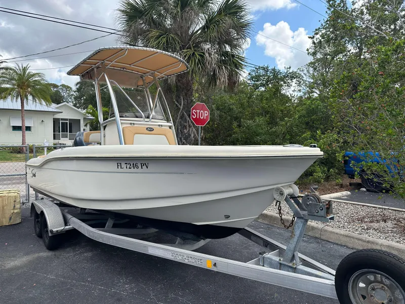 Slide: The Image of 2014 Scout 215 XSF boat on trailer, parked near palm trees and stop sign. - 3