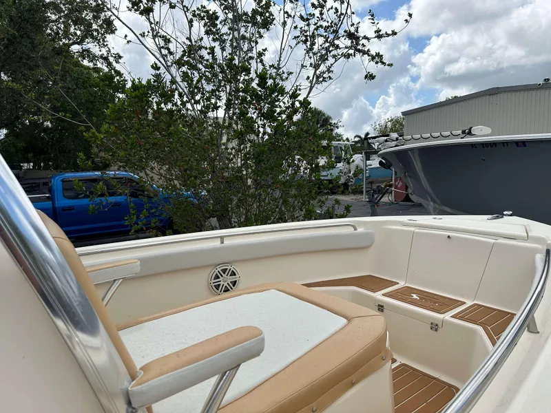 Slide: The Image of 2014 Scout 215 XSF boat interior with seating, parked near trees and vehicles. - 5