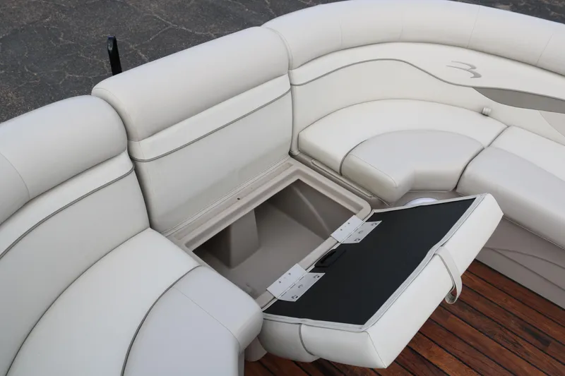 Slide: The Image of 2015 Bennington 22SSLDX boat with open storage compartment on white cushioned seating. - 15