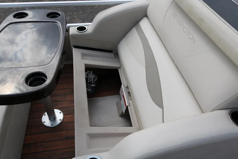 Slide: The Image of 2015 Bennington 22SSLDX boat interior with seating and table, showcasing storage space. - 31