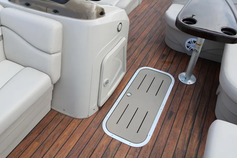 Slide: The Image of 2015 Bennington 22SSLDX boat interior with wood flooring and beige seating. - 34