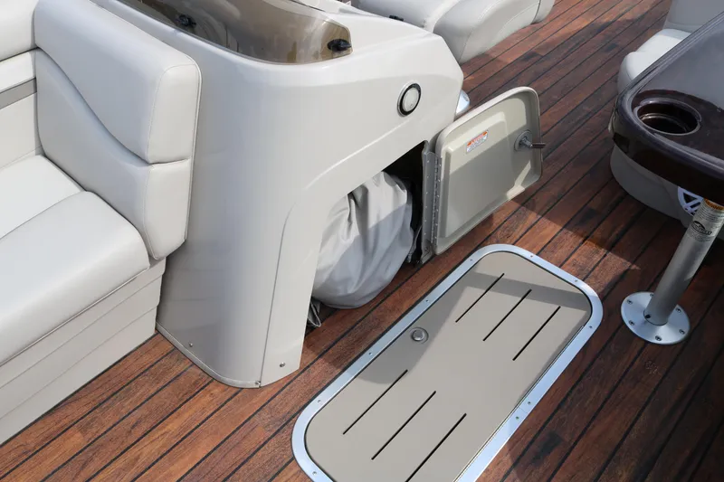 Slide: The Image of 2015 Bennington 22SSLDX boat interior with storage compartment and seating on wooden deck. - 35