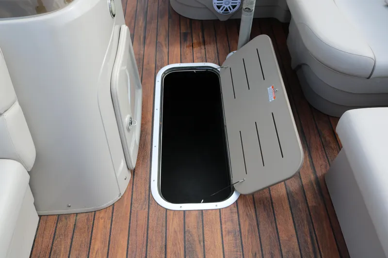 Slide: The Image of 2015 Bennington 22SSLDX boat interior with open storage compartment on wooden deck. - 37