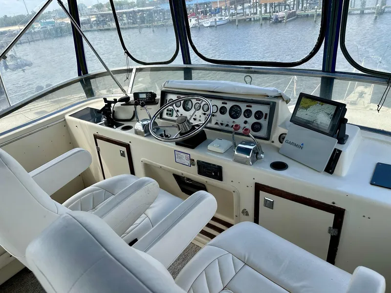 Slide: The Image of 1986 Chris-Craft Yacht Fisherman helm with steering wheel, navigation equipment, and white seating. - 11