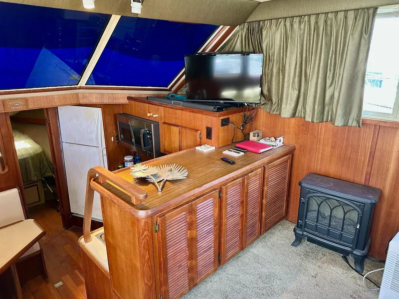 Slide: The Image of 1986 Chris-Craft Yacht Fisherman interior with wood paneling, TV, and kitchenette. - 23