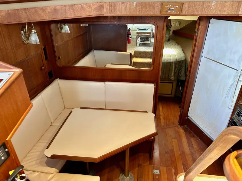 Slide: The Image of 1986 Chris-Craft Yacht Fisherman interior with dining area, wood paneling, and cozy seating. - 29