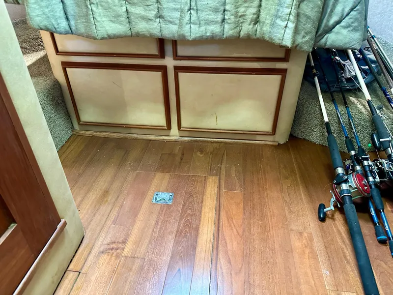 Slide: The Image of 1986 Chris-Craft Yacht Fisherman interior with fishing rods and wooden flooring. - 31