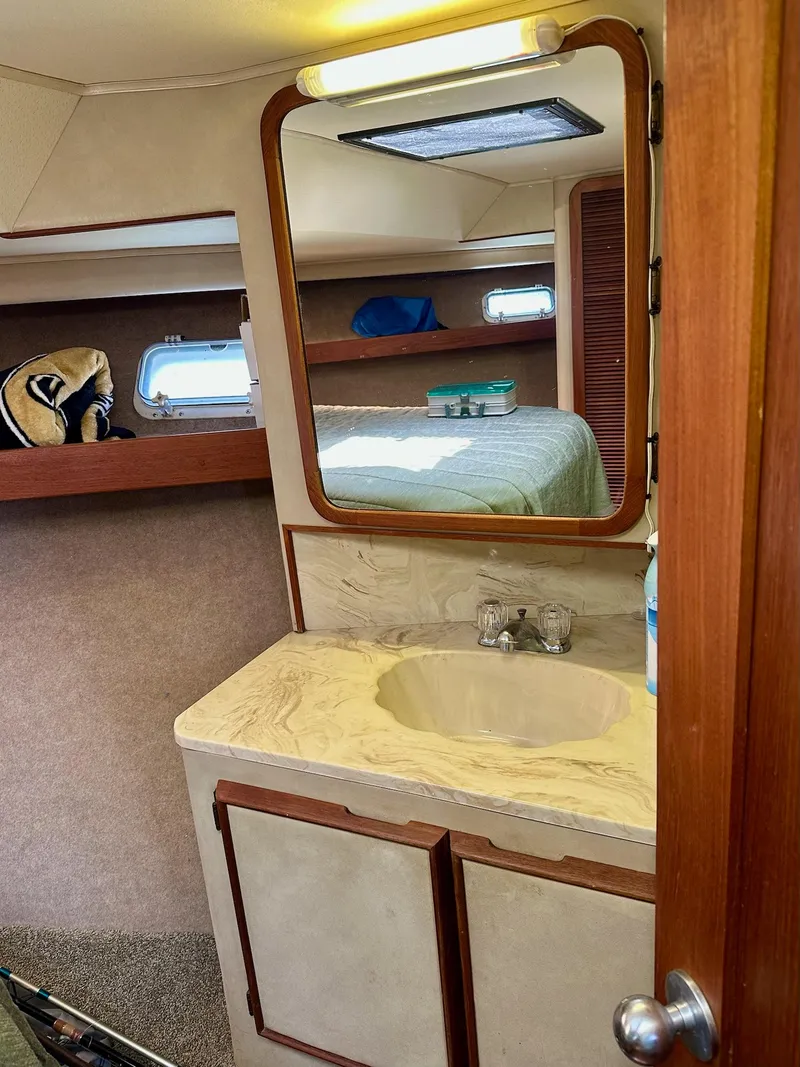 Slide: The Image of 1986 Chris-Craft Yacht Fisherman interior with sink, mirror, and cozy sleeping area. - 32