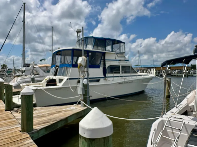 Slide: The Image of 1986 Chris-Craft Yacht Fisherman docked at a marina under a cloudy sky. - 4