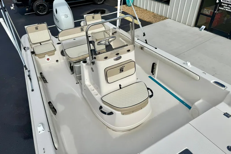 Slide: The Image of 2024 Carolina Skiff 19 LS boat interior with seating and console, docked outdoors. - 16