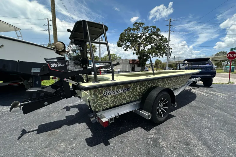 Slide: The Image of 2025 Sawgrass 17 boat on trailer, camo design, parked outdoors under blue sky. - 14