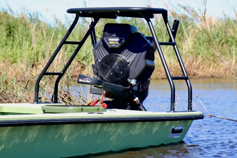 Slide: The Image of 2025 Sawgrass 17 boat with powerful engine, floating on calm water near grassy shoreline. - 3