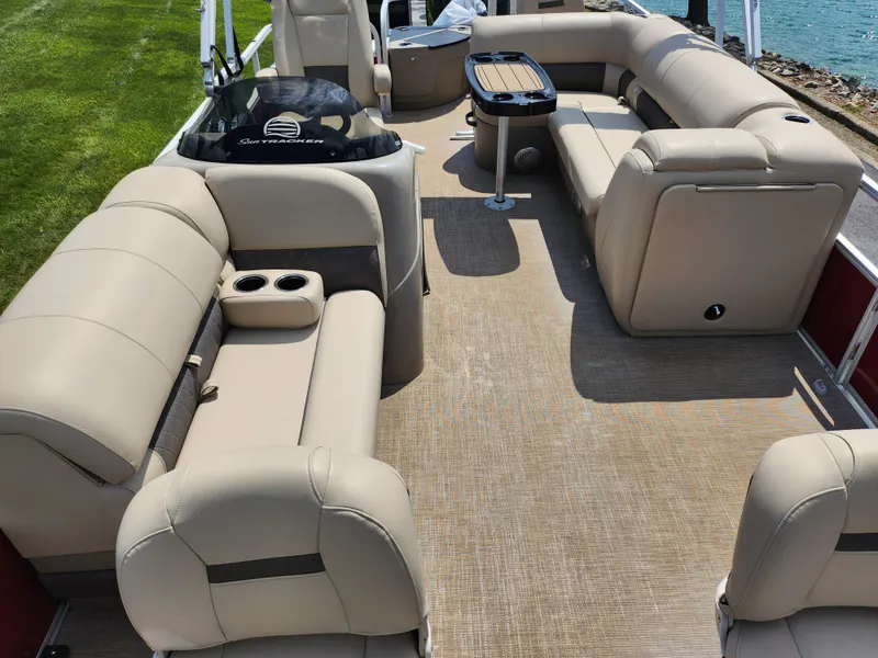 Slide: The Image of 2021 Sun Tracker Fishin' Barge 20 DLX interior with beige seating and a central table. - 11