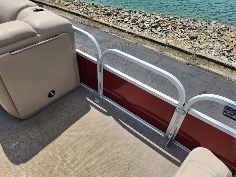 Slide: The Image of 2021 Sun Tracker Fishin' Barge 20 DLX interior with beige seating and red paneling by the water. - 12
