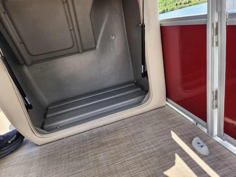 Slide: The Image of 2021 Sun Tracker Fishin' Barge 20 DLX storage compartment with red exterior and carpeted floor. - 14
