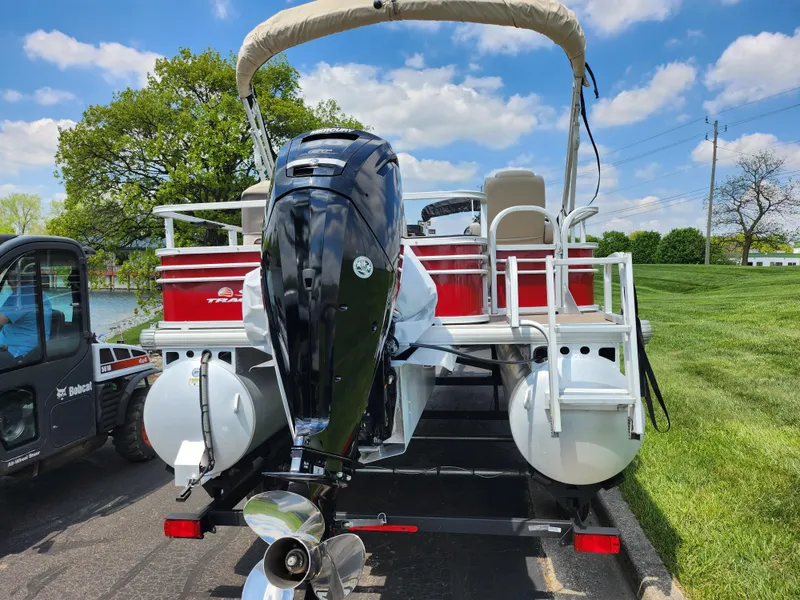 Slide: The Image of 2021 Sun Tracker Fishin' Barge 20 DLX pontoon boat on trailer, parked outdoors. - 2