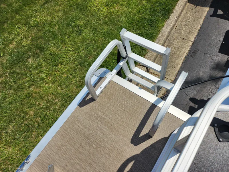 Slide: The Image of 2021 Sun Tracker Fishin' Barge 20 DLX boat ladder and deck, near grass and pavement. - 22