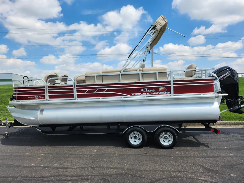 Slide: The Image of 2021 Sun Tracker Fishin' Barge 20 DLX pontoon boat on trailer, under blue sky. - 4