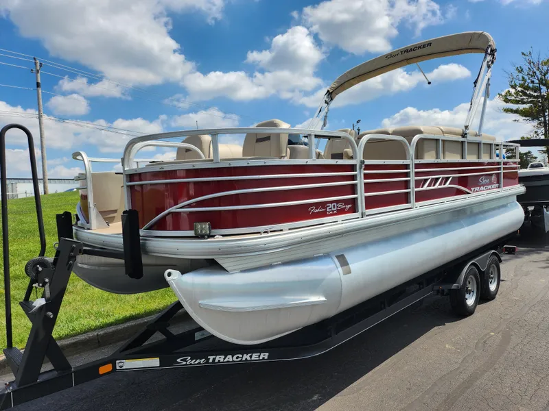 Slide: The Image of 2021 Sun Tracker Fishin' Barge 20 DLX pontoon boat on trailer, under blue sky. - 5