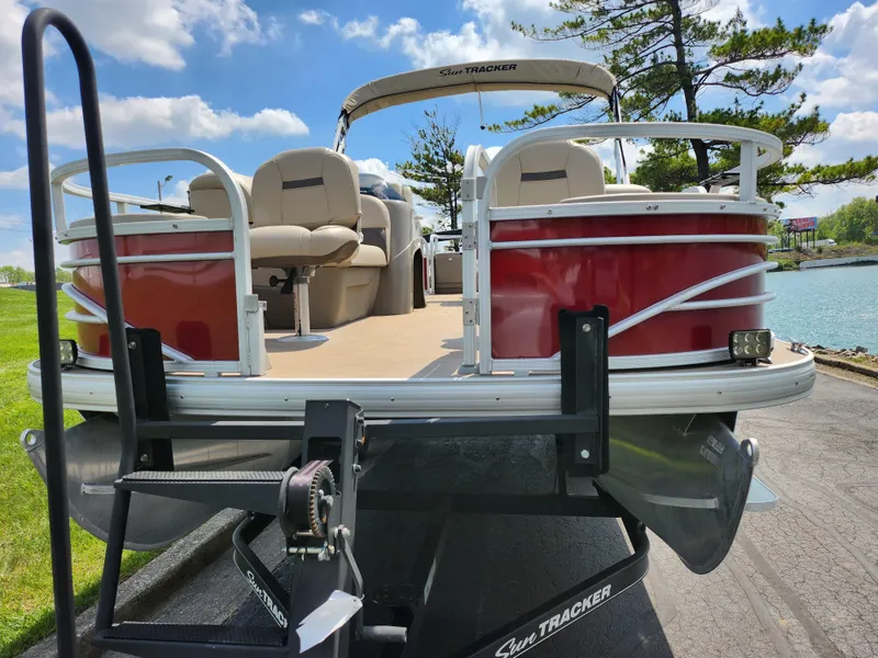 Slide: The Image of 2021 Sun Tracker Fishin' Barge 20 DLX pontoon boat on trailer by a lake. - 6
