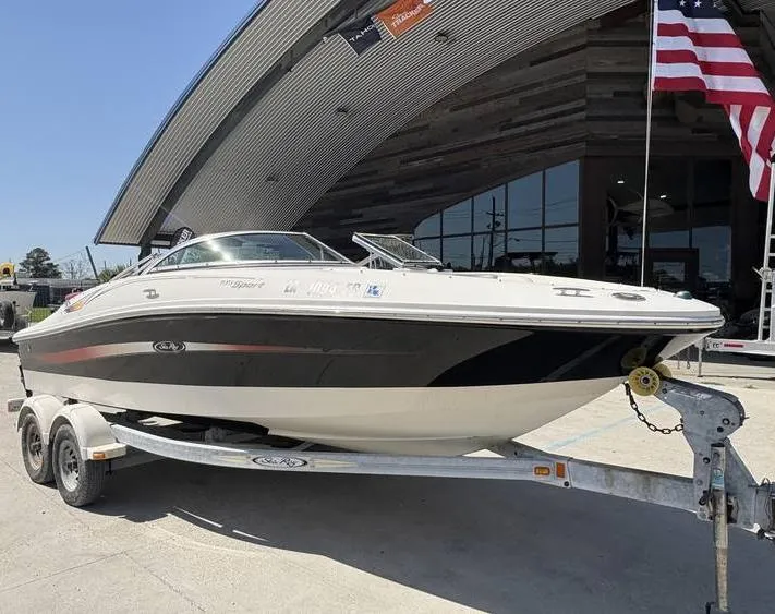 Slide: The Image of 2007 Sea Ray 195 Sport boat on trailer, parked outside a modern building with American flag. - 2