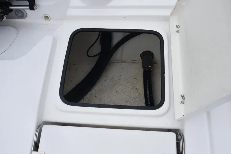 Slide: The Image of 2017 Blazer Bay 2200 boat storage compartment with open hatch and visible hose. - 25