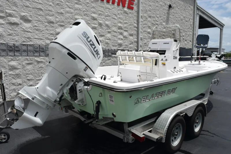 Slide: The Image of 2017 Blazer Bay 2200 boat with Suzuki engine on a trailer, parked outside a building. - 4