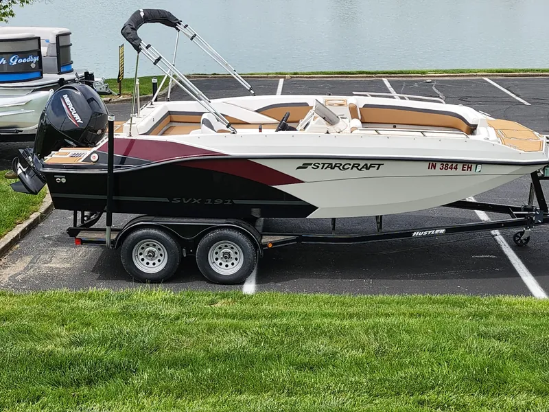 Slide: The Image of 2021 Starcraft SVX 191 OB boat on trailer, parked near a lake. - 0