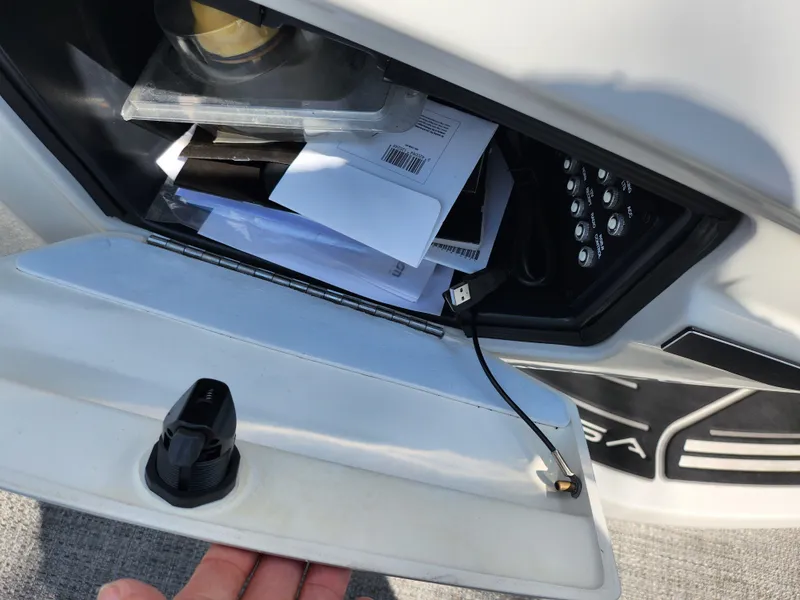 Slide: The Image of Storage compartment in a 2021 Barletta CORSA 23QC boat, containing documents and a USB cable. - 22