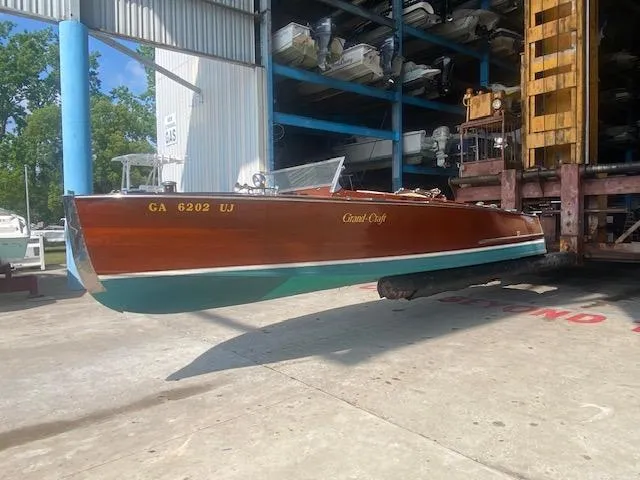 Slide: The Image of Grand Craft Classic Runabout 2000 boat in storage, featuring a wooden hull and elegant design. - 32