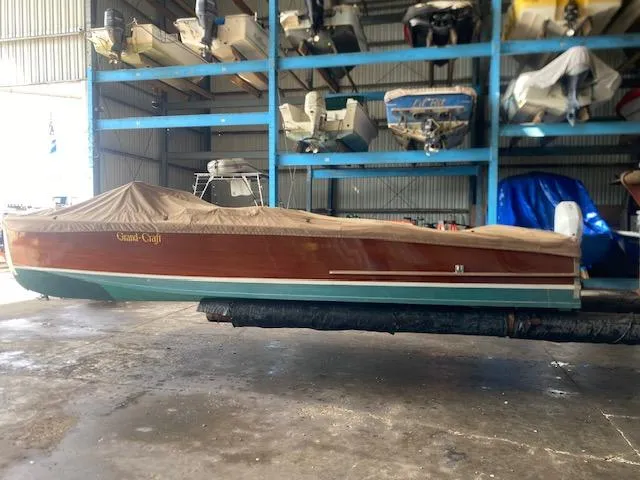 Slide: The Image of Grand Craft Classic Runabout 2000 in storage, covered, with other boats in the background. - 14