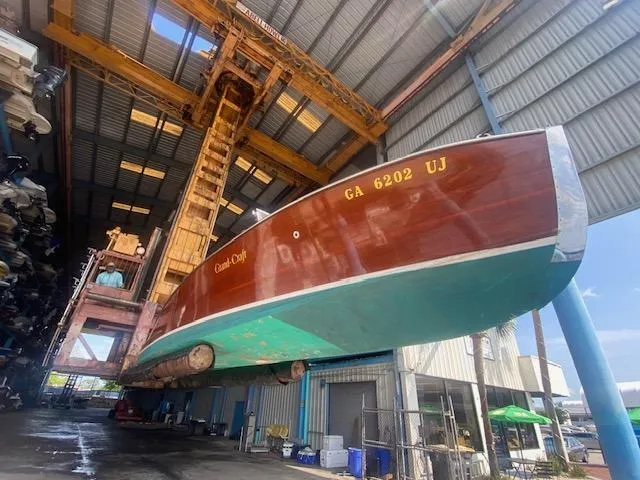 Slide: The Image of Grand Craft Classic Runabout 2000 in a boatyard, suspended for maintenance or storage. - 2