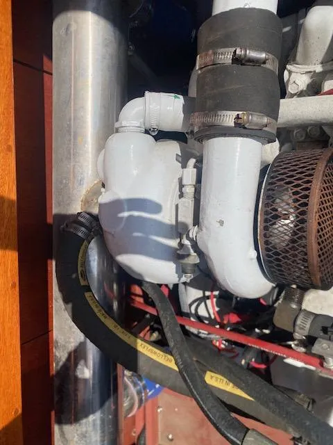 Slide: The Image of Engine components of a 2000 Grand Craft Classic Runabout boat, featuring hoses and metal parts. - 23