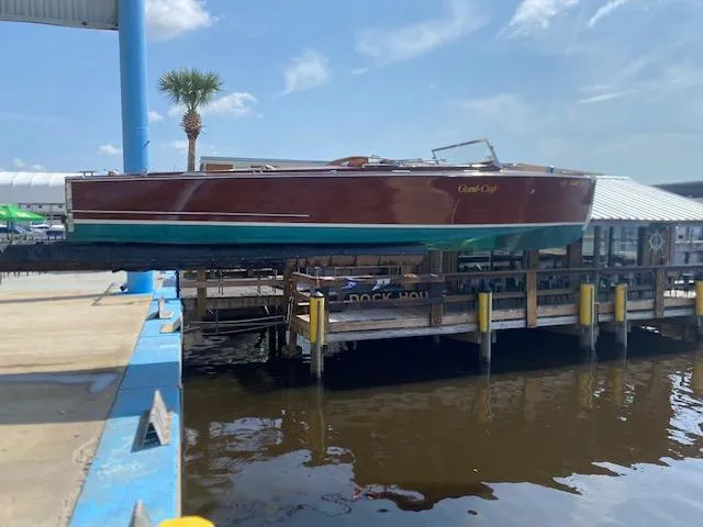 Slide: The Image of Grand Craft Classic Runabout 2000 on dock, wooden design, sunny day, palm tree nearby. - 27