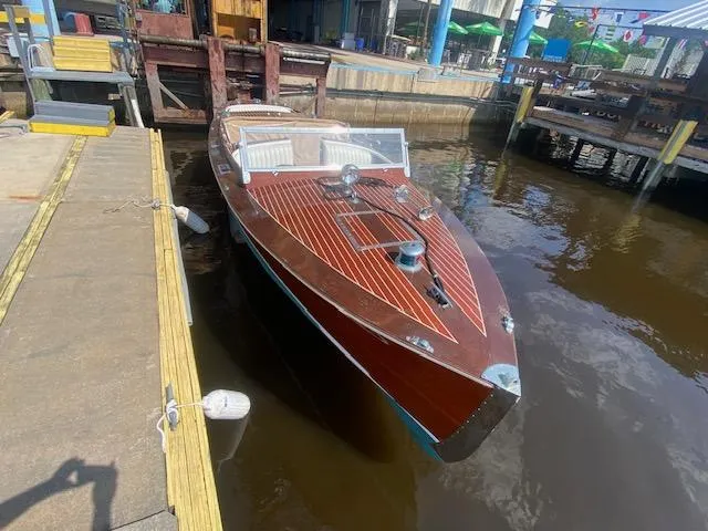 Slide: The Image of 2000 Grand Craft Classic Runabout boat docked at a marina, showcasing elegant wooden design. - 28