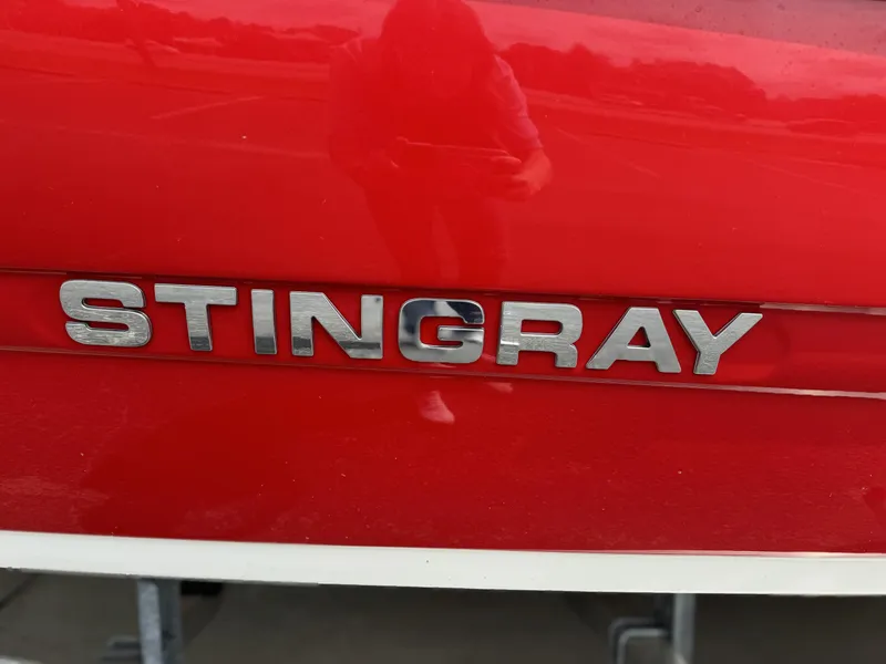 Slide: The Image of 2021 Stingray 182 SC boat with red hull on trailer, parked outdoors. - 8