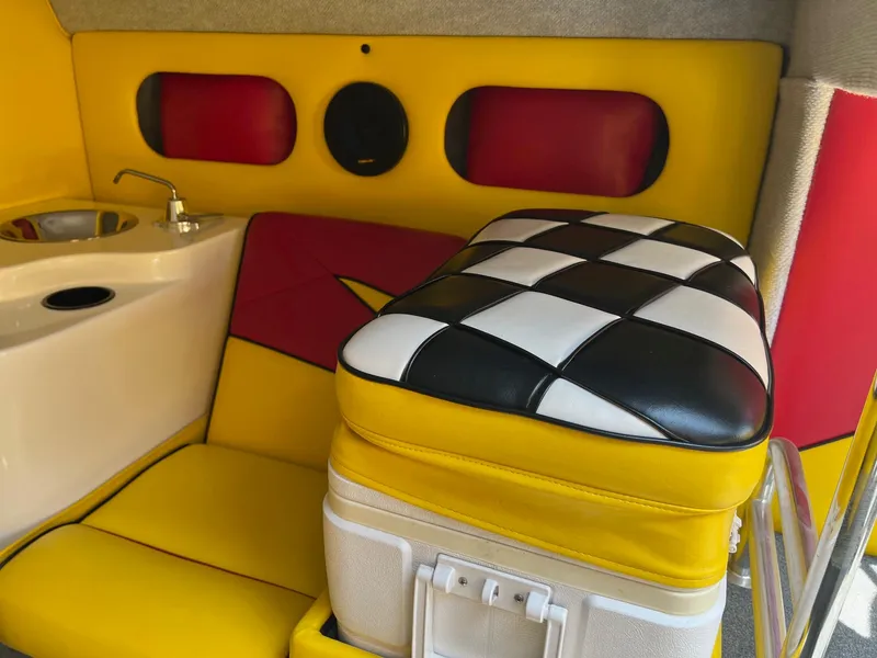 Slide: The Image of Interior of 2006 Kachina Drone 26 with vibrant yellow and red seating, checkered cushion, and sink. - 12