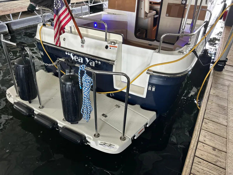 Slide: The Image of 2016 Ranger Tugs R-25SC boat docked, rear view with American flag and fenders. - 10