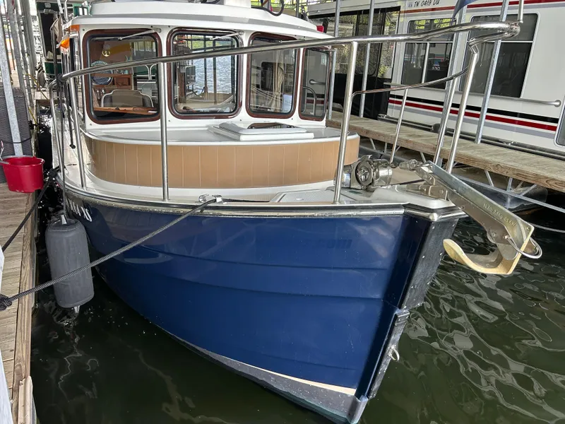 Slide: The Image of 2016 Ranger Tugs R-25SC boat docked, featuring a blue hull and enclosed cabin. - 11