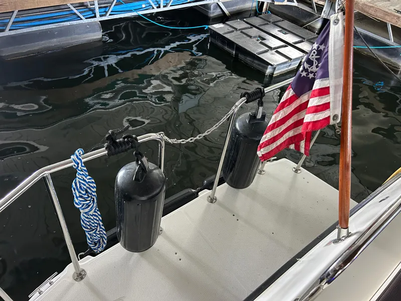 Slide: The Image of 2016 Ranger Tugs R-25SC boat stern with fenders and American flag at dock. - 21